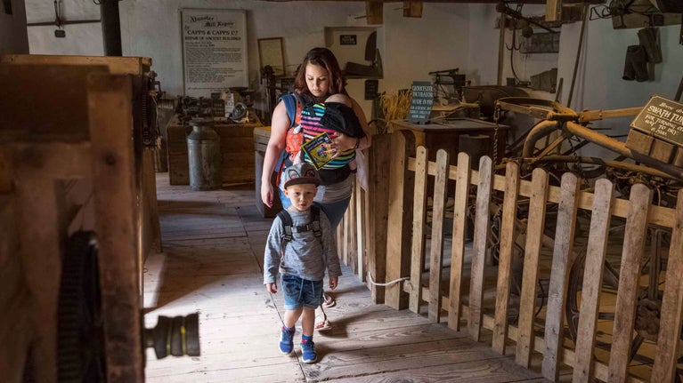 An adult and children explore inside the working watermill at Dunster Castle, Somerset
